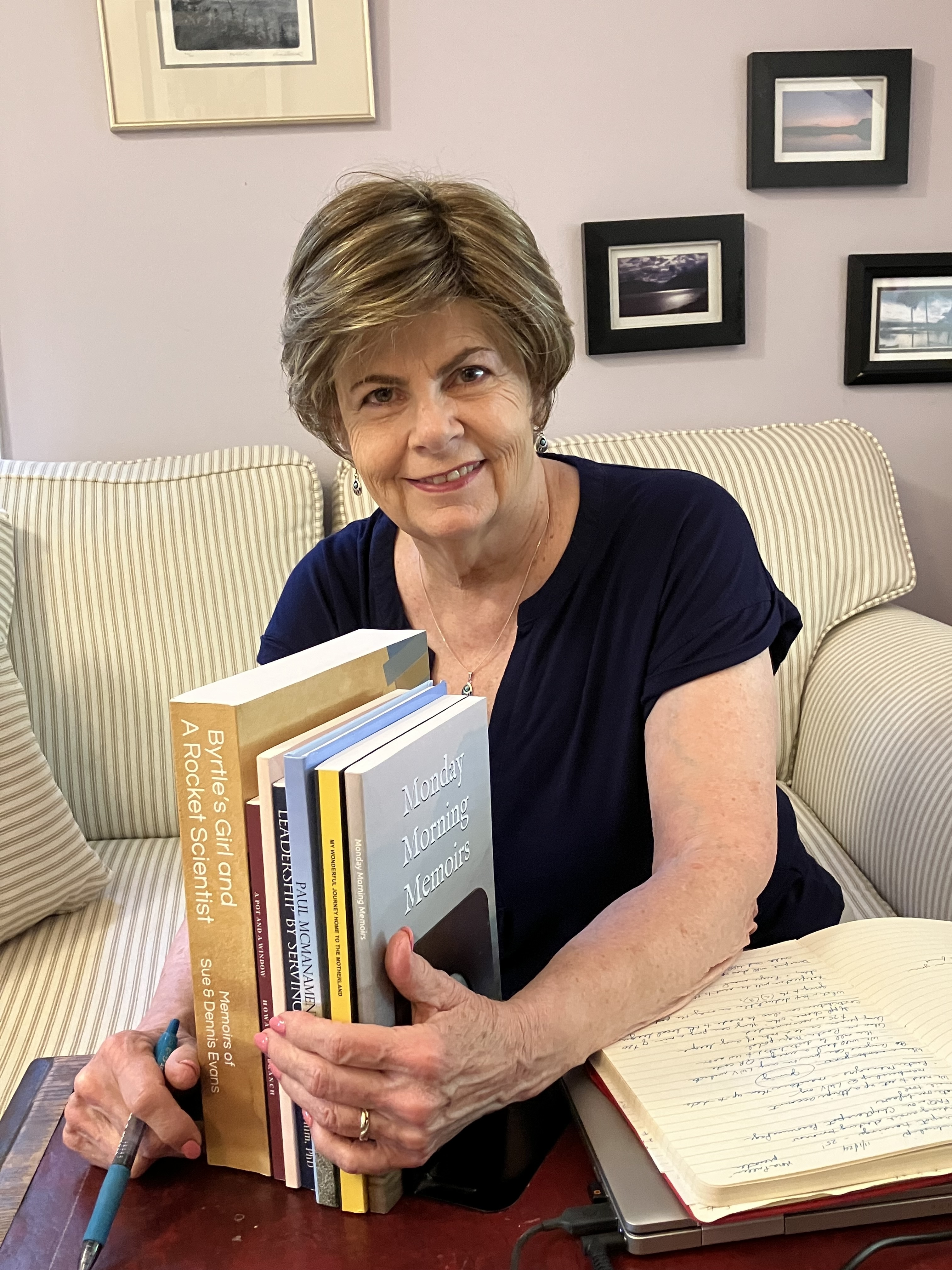 PGCC Adjunct Professor Cathy Smith poses with a collection of published memoirs from SAGE students in her writing class at the College.