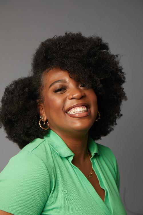 Kendall Andrews smiles in a portrait in a light green shirt and gold earrings.