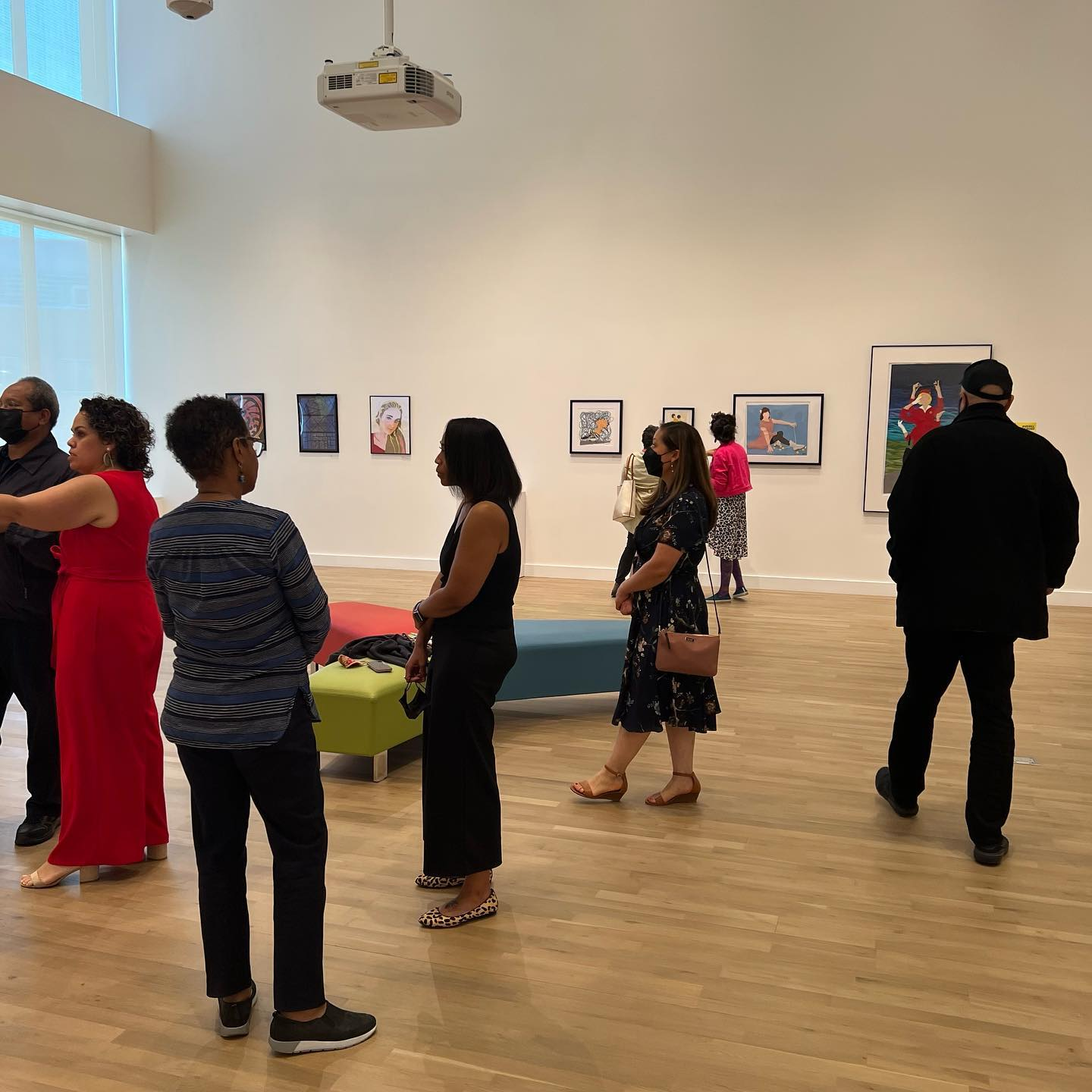 Visitors viewing artwork and conversing in a bright, modern art gallery.