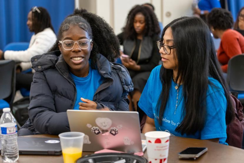 Two students working together on a laptop during a cybersecurity training session