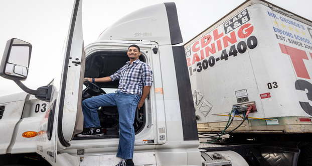 CDL Student is standing outside the door of the commercial truck