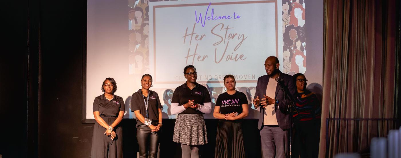 A group of W.O.W. participants stand on stage at an event for the program.